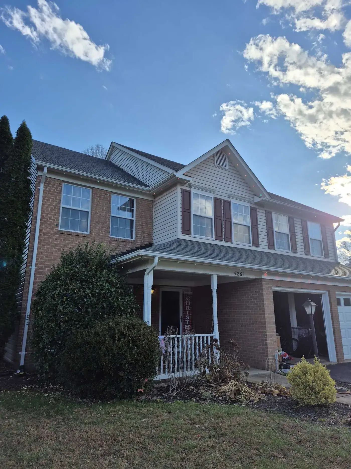 Front elevation of a brick and siding home with permanent lighting fitted along the roofline and porch.