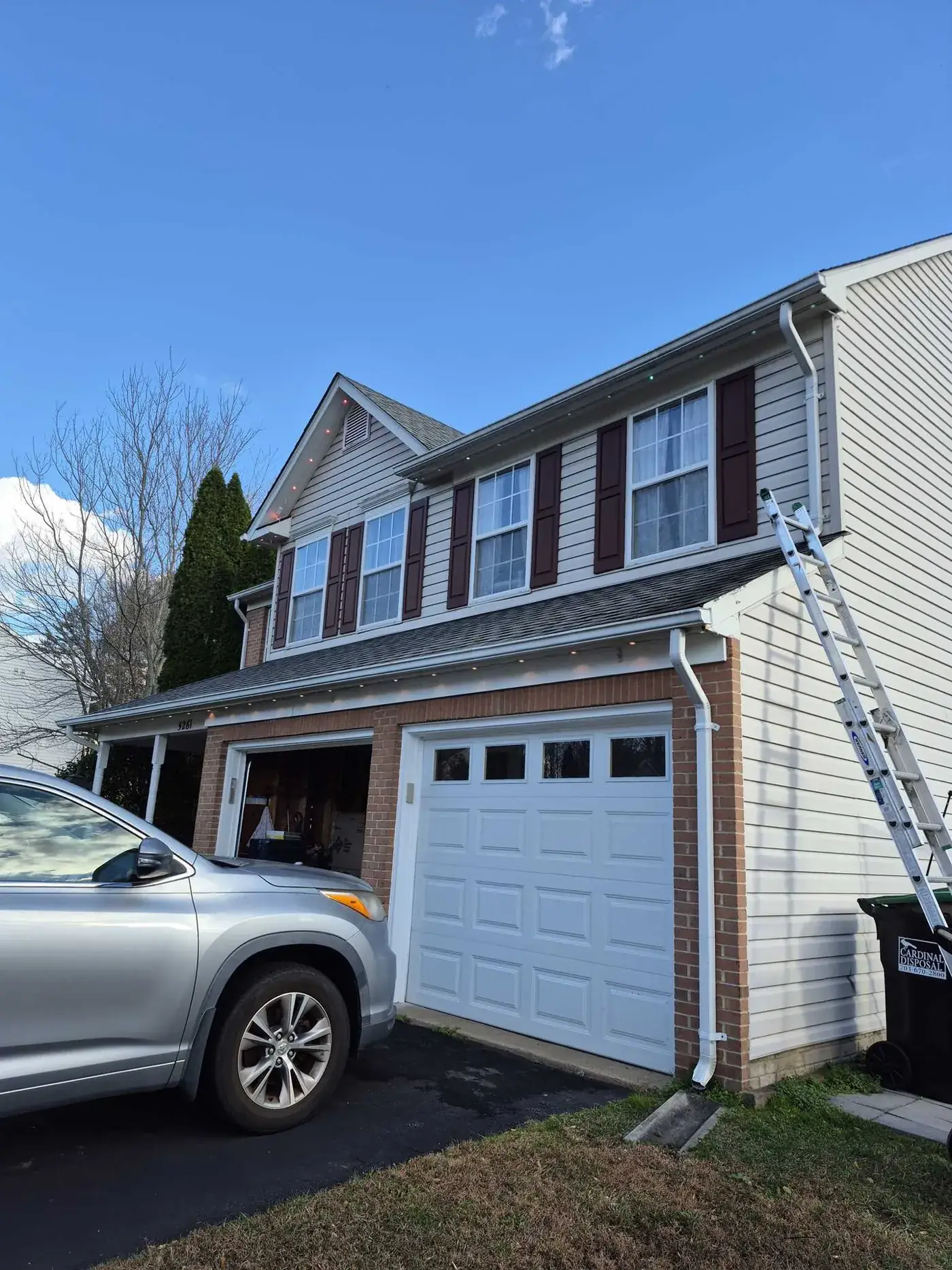 Ladder against the side of a house during installation of soffit lighting above the garage.